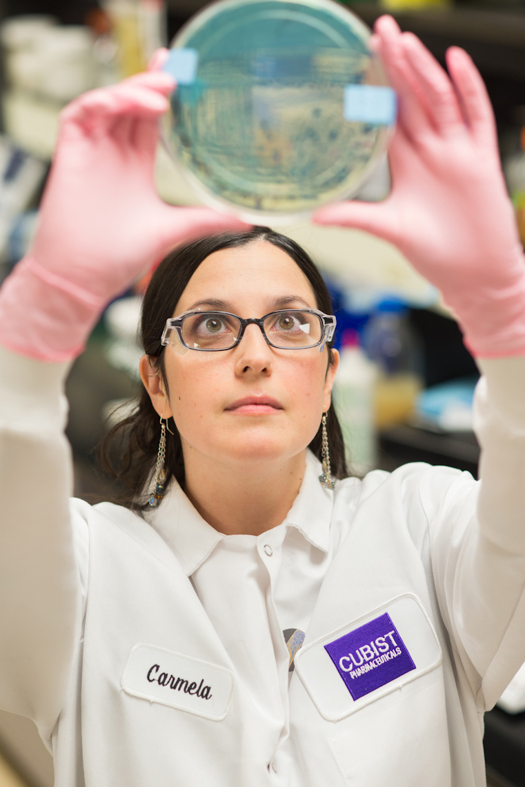 female lab worker holding up petri dish at Cubist