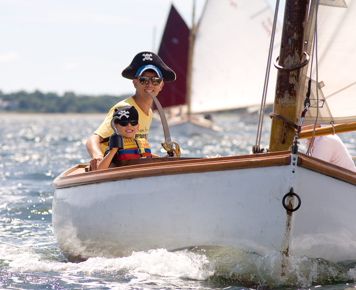 Child and father wearing pirate hats on sailboat